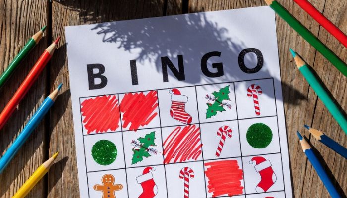 Christmas reading challenge bingo card with coloured pencils and open book - Grok Imagine