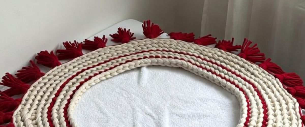 Chunky knitted Christmas tree skirt laid flat on a white towel to dry after hand washing - ai image